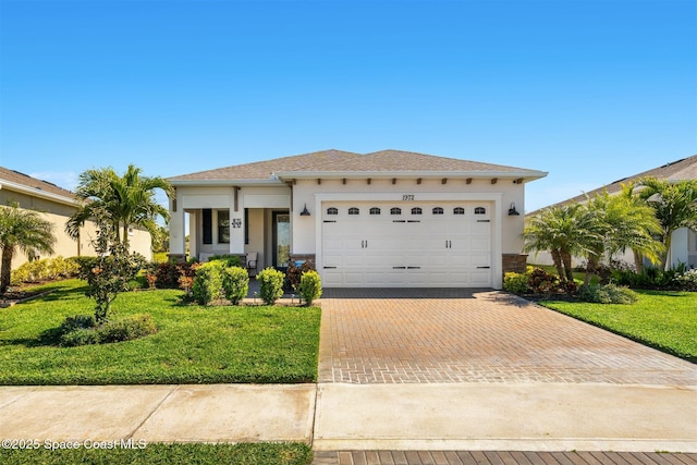 view of front of property with decorative driveway, a front yard, and stucco siding