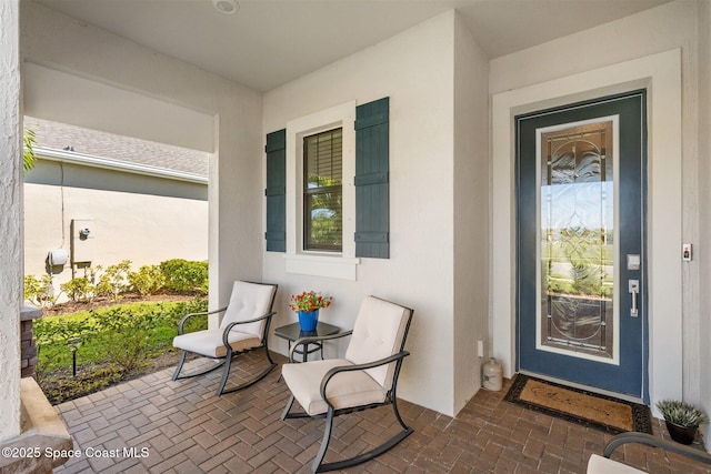 property entrance with stucco siding and covered porch