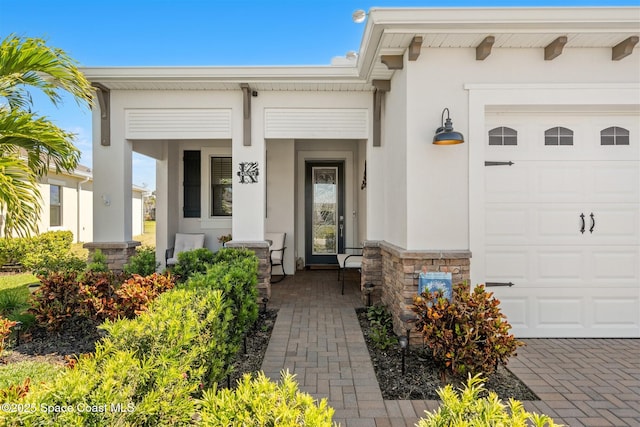 doorway to property featuring stucco siding, covered porch, and an attached garage