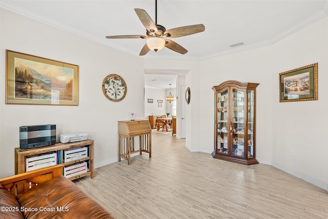 living area featuring visible vents, light wood-style flooring, ceiling fan, and ornamental molding