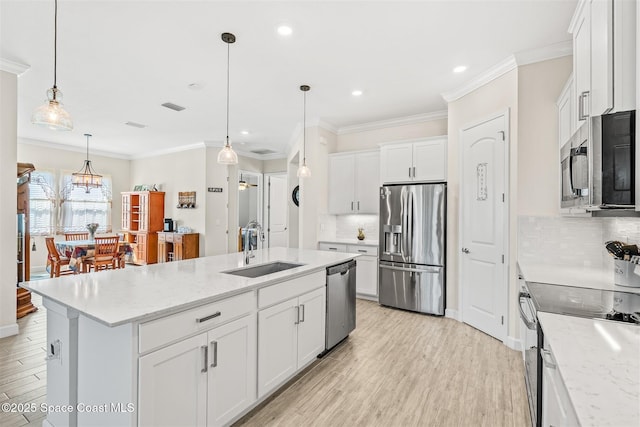 kitchen featuring light wood-style flooring, an island with sink, a sink, ornamental molding, and stainless steel appliances