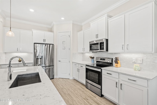 kitchen with a sink, crown molding, white cabinetry, and stainless steel appliances