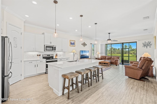 kitchen with visible vents, a sink, backsplash, open floor plan, and appliances with stainless steel finishes