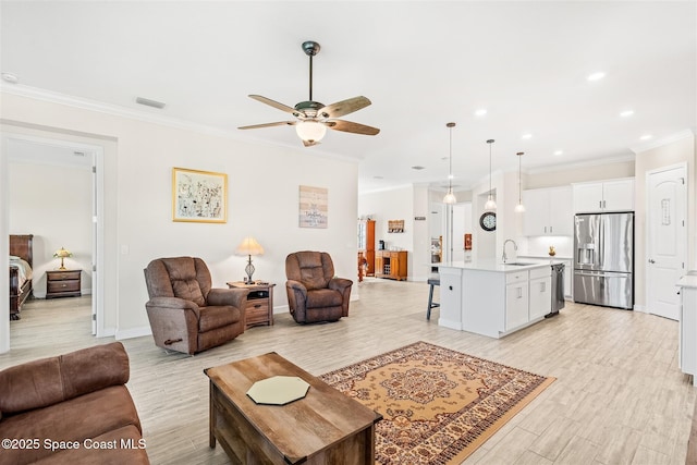 living room with visible vents, light wood-style flooring, crown molding, and a ceiling fan