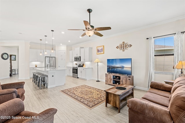 living area featuring light wood-style flooring, baseboards, ornamental molding, and a ceiling fan