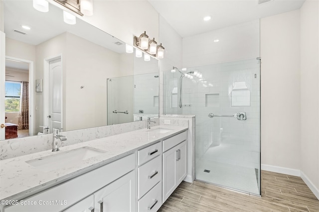 ensuite bathroom featuring a sink, wood tiled floor, and a tile shower