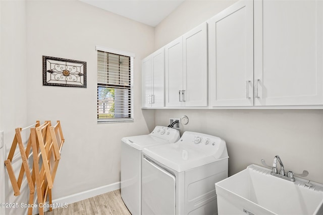 laundry room with baseboards, cabinet space, a sink, light wood-style floors, and washer and dryer