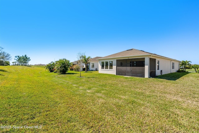 rear view of property featuring stucco siding, a yard, a garage, and a sunroom