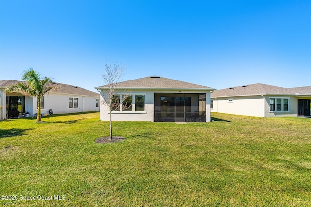 back of property with a lawn, a sunroom, and stucco siding