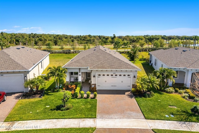 view of front of property featuring decorative driveway, an attached garage, a front lawn, and stucco siding