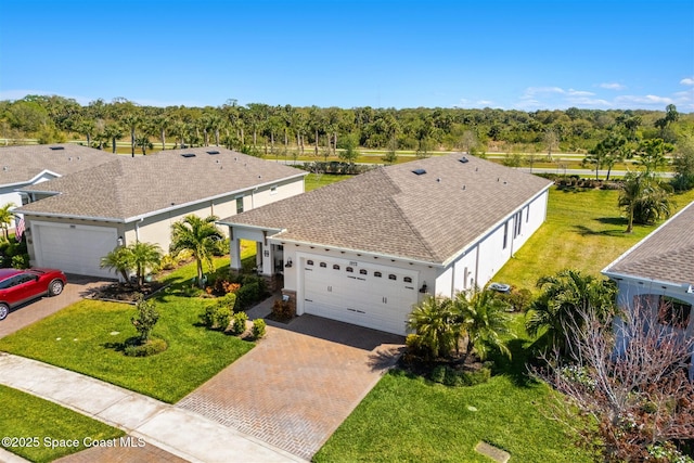 view of front of home featuring decorative driveway, a front lawn, an attached garage, and roof with shingles