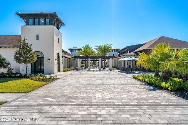 view of community featuring decorative driveway and a pergola