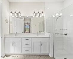 full bath with double vanity, wood finished floors, and a stall shower