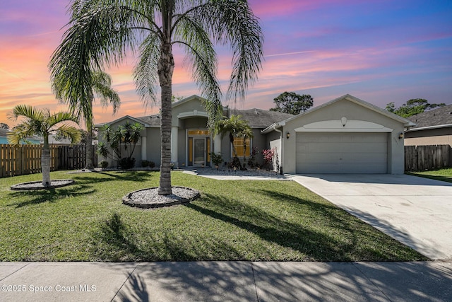 view of front of property featuring stucco siding, driveway, fence, a yard, and an attached garage