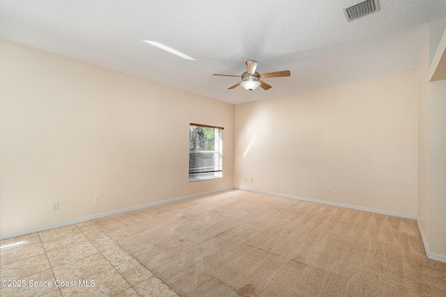 empty room with visible vents, baseboards, ceiling fan, light colored carpet, and a textured ceiling