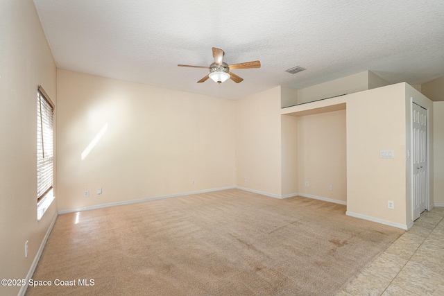 spare room featuring baseboards, visible vents, ceiling fan, a textured ceiling, and light carpet