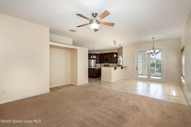 unfurnished living room featuring visible vents, ceiling fan with notable chandelier, a textured ceiling, light tile patterned flooring, and light colored carpet