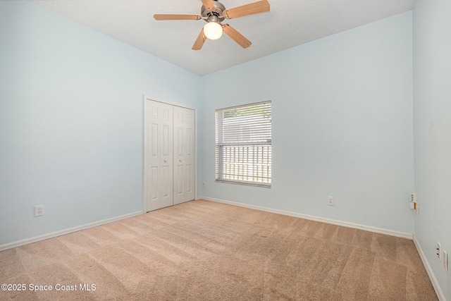 spare room with baseboards, light colored carpet, and ceiling fan