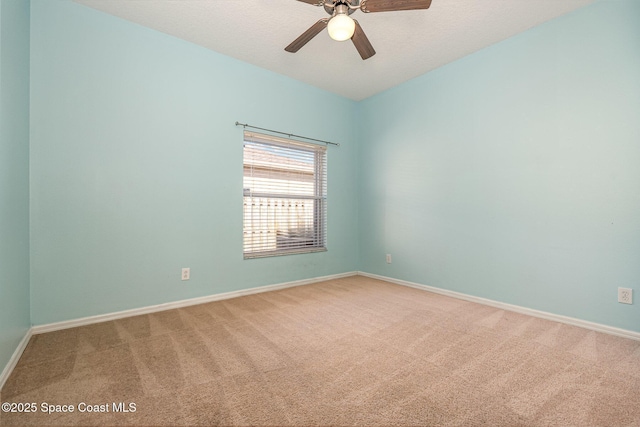 carpeted spare room with baseboards and a ceiling fan