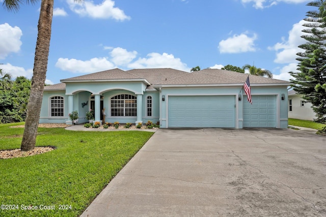 ranch-style home featuring a front lawn, an attached garage, concrete driveway, and stucco siding