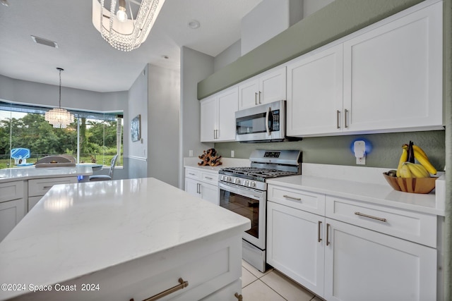 kitchen featuring visible vents, light stone countertops, stainless steel appliances, an inviting chandelier, and white cabinetry