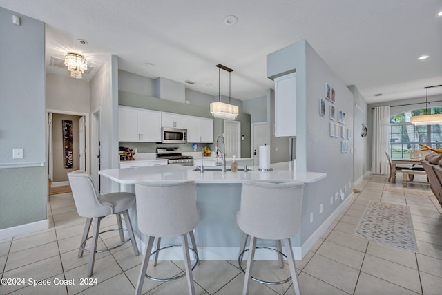 kitchen with a breakfast bar, a sink, stainless steel appliances, light countertops, and white cabinets