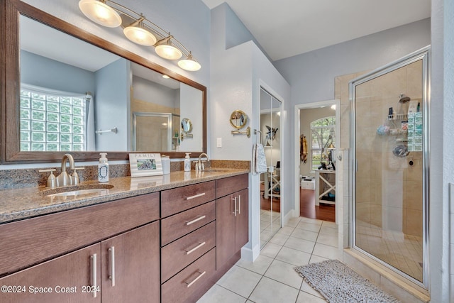 bathroom featuring tile patterned floors, a stall shower, double vanity, and a sink