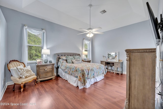 bedroom featuring visible vents, a ceiling fan, baseboards, and wood finished floors