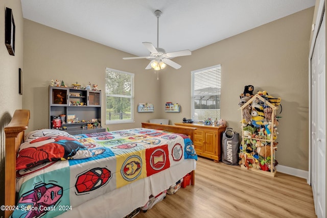 bedroom featuring light wood-type flooring, multiple windows, baseboards, and ceiling fan