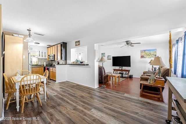 dining space with dark wood finished floors, visible vents, baseboards, and a ceiling fan