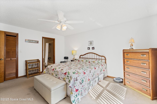 bedroom featuring baseboards, light colored carpet, ensuite bath, and a textured ceiling