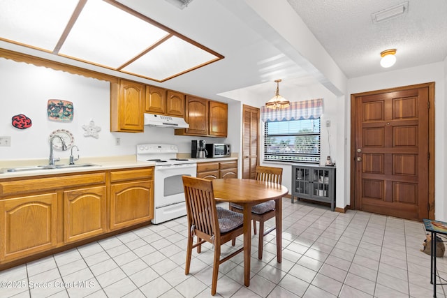 kitchen with under cabinet range hood, light tile patterned floors, electric stove, brown cabinetry, and a sink