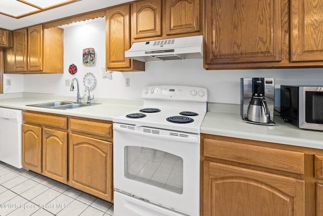 kitchen featuring under cabinet range hood, light countertops, brown cabinets, white appliances, and a sink