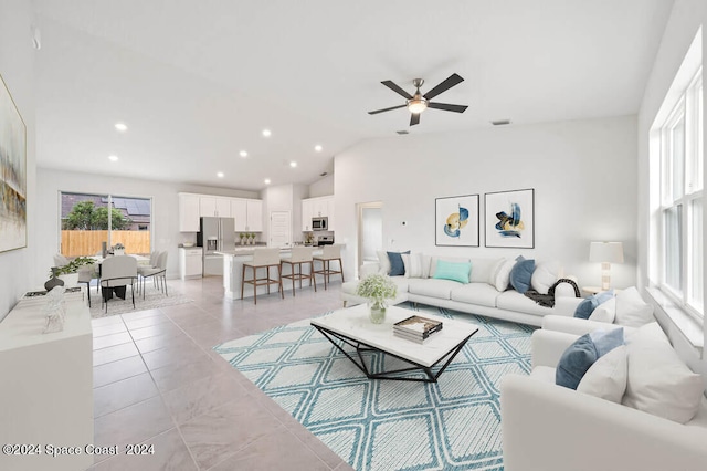 living room featuring lofted ceiling, light tile patterned floors, a ceiling fan, and a wealth of natural light