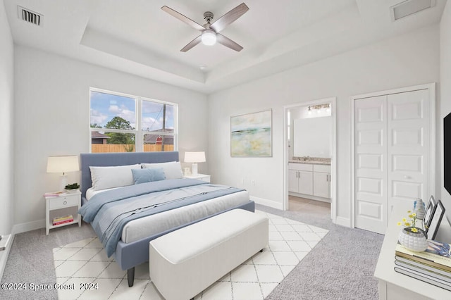 bedroom featuring visible vents, connected bathroom, baseboards, light colored carpet, and a tray ceiling