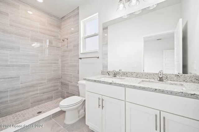 full bath with double vanity, toilet, a tile shower, and a sink