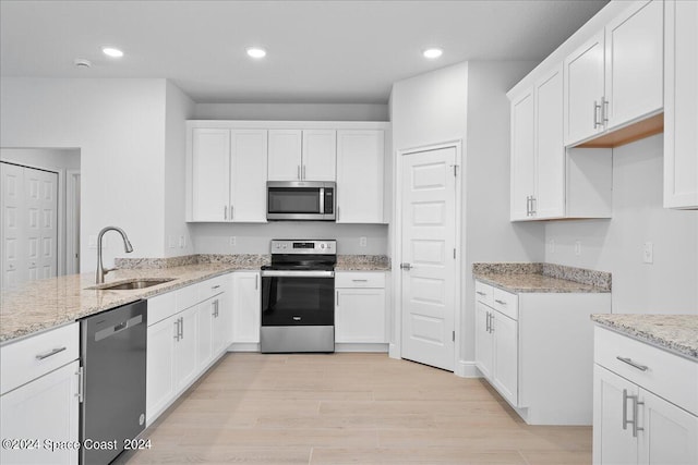 kitchen featuring light wood-style flooring, a sink, recessed lighting, appliances with stainless steel finishes, and light stone countertops