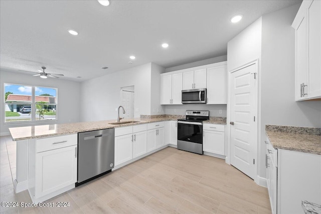 kitchen with white cabinetry, a peninsula, appliances with stainless steel finishes, and a sink