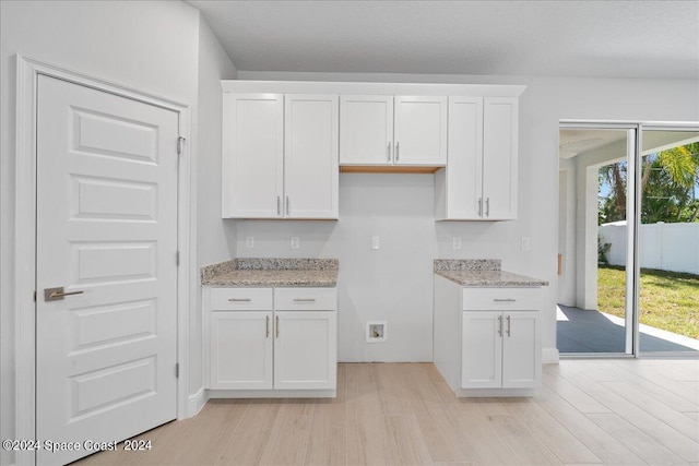 kitchen featuring light stone counters, white cabinetry, and light wood-style floors