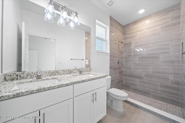 full bathroom featuring a sink, visible vents, toilet, and a tile shower