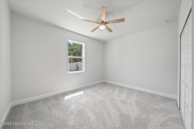 carpeted spare room with baseboards, a textured ceiling, and a ceiling fan