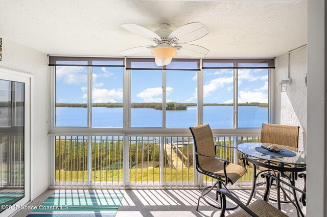 sunroom featuring a wealth of natural light, a water view, and ceiling fan