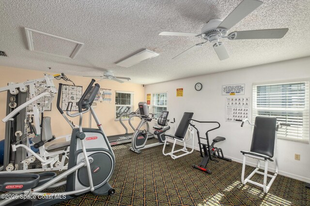 exercise room featuring baseboards, visible vents, a textured ceiling, and attic access