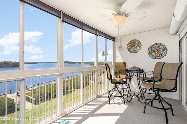 sunroom with a ceiling fan and a water view