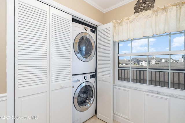 laundry area featuring laundry area, stacked washer / dryer, and ornamental molding