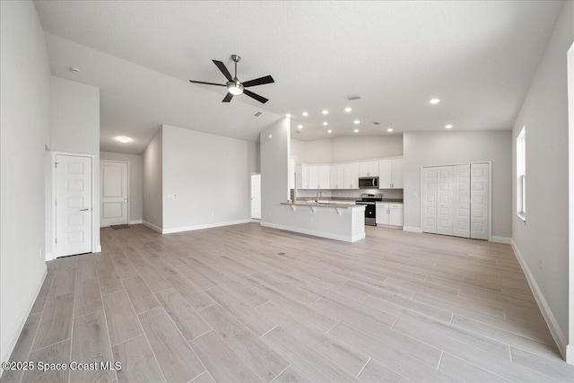 unfurnished living room with visible vents, baseboards, light wood-style floors, and ceiling fan