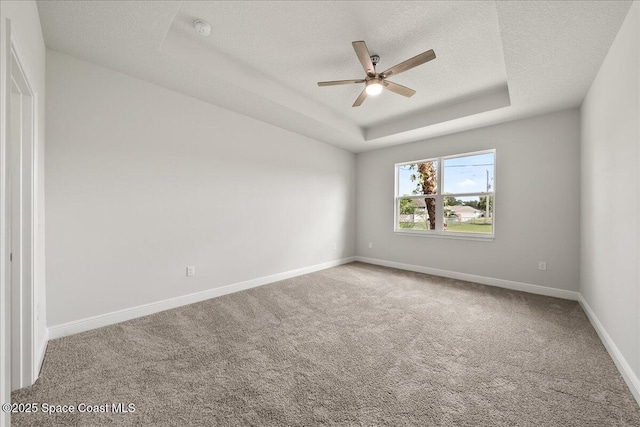 carpeted empty room with a raised ceiling, a ceiling fan, baseboards, and a textured ceiling