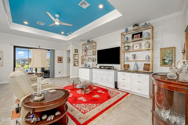 living area with visible vents, a tray ceiling, and ornamental molding