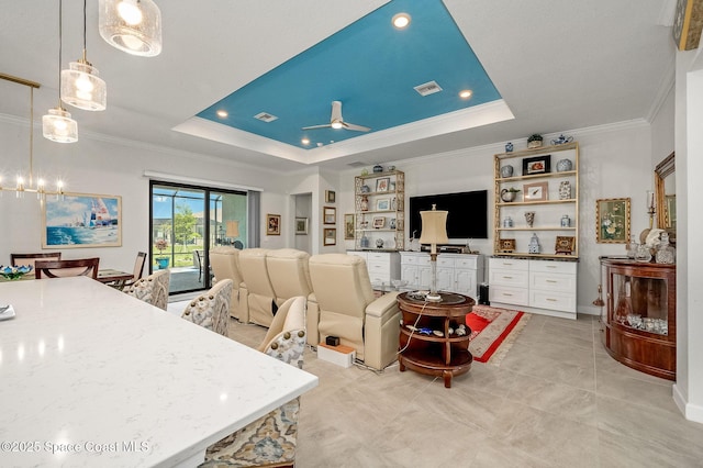 living room featuring a tray ceiling, visible vents, and ceiling fan