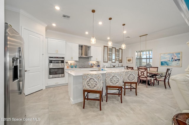 kitchen featuring visible vents, appliances with stainless steel finishes, wall chimney exhaust hood, crown molding, and light countertops